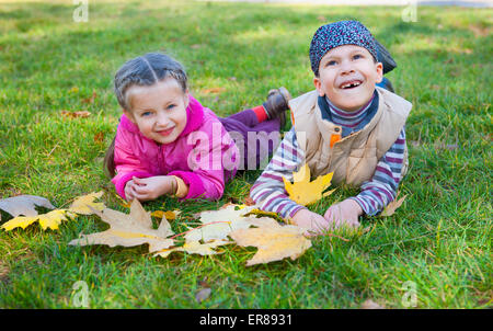 Enfant se trouve de l'herbe dans le parc en automne Banque D'Images