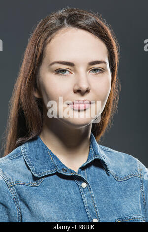 Portrait de la belle jeune femme portant veste en jean sur fond gris Banque D'Images