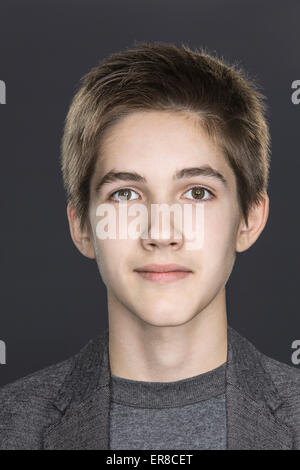 Close-up portrait of smiling teenage boy sur fond gris Banque D'Images