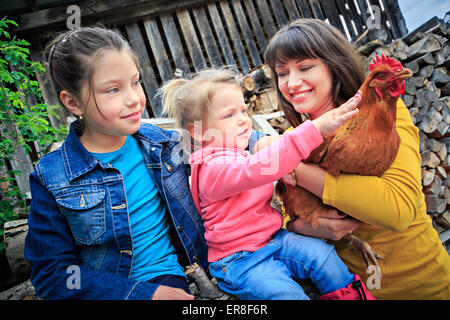 Une famille agricole avec une poule en face de la ferme Banque D'Images