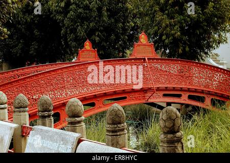 Bangkok, Thaïlande : un pont en fer forgé ornemental enjambe un klong avec graminées ornementales bouddhiste au Wat Benchambophit Banque D'Images