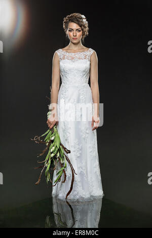 Portrait de sad young bride holding bouquet flétri en étant debout dans l'eau contre l'arrière-plan gris Banque D'Images