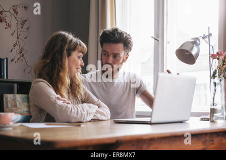 Young couple having discussion avec ordinateur portable sur la table à la maison Banque D'Images