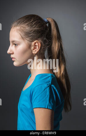 Vue latérale du sad Girl standing against gray background Banque D'Images