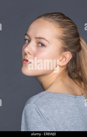 Vue de côté portrait of teenage girl contre l'arrière-plan gris Banque D'Images