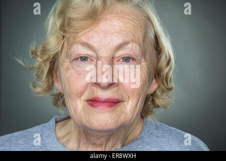 Close-up portrait of smiling senior woman contre l'arrière-plan gris Banque D'Images