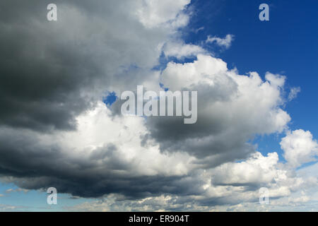 Les nuages de tempête formant une courbe à travers un ciel bleu. Très peu de nuages avec base noire et silver linings Banque D'Images