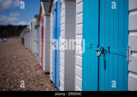 Une rangée de cabanes de plage avec portes colorées sur la plage de galets, Devon, UK Banque D'Images