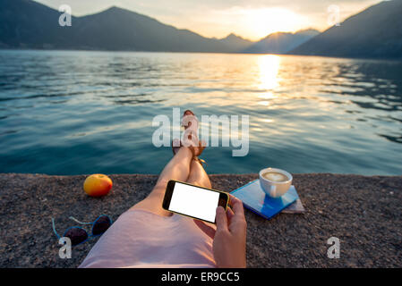 Woman holding phone lying on the pier Banque D'Images