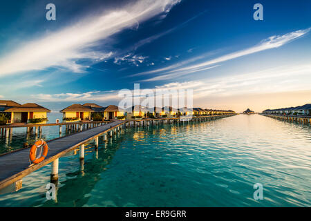 L'heure du coucher du soleil sur l'île des Maldives sur le pont au-dessus de l'eau reliant bungallows Banque D'Images