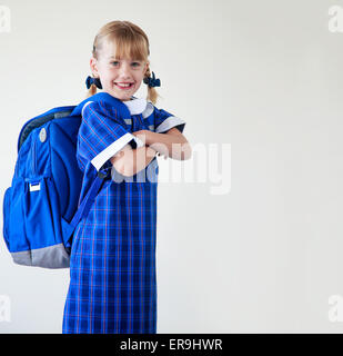 Petite fille vêtue de son uniforme scolaire sac à dos et prêt à aller à l'école Banque D'Images