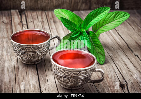 Deux bols en fer avec tisane sur fond de feuilles de menthe Banque D'Images