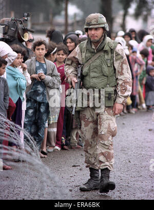 23 mars 1991 un soldat de l'armée américaine garde une ligne ordonnée d'Irakiens déplacés, faisant la queue pour la nourriture et les boissons près de Safwan dans le sud de l'Irak.