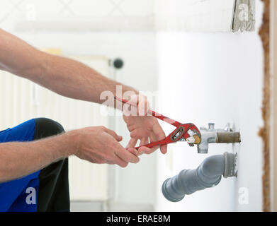 Close-up des mains du plombier travaillant sur un tuyau avec une clé Banque D'Images