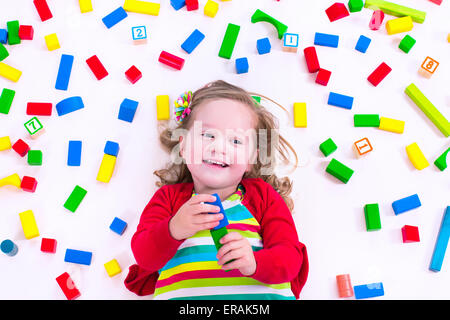 Enfant jouant avec des jouets en bois. Petite fille jouet éducatif avec des blocs. Les enfants jouent à l'âge préscolaire. Désordre dans chambre d'enfant Banque D'Images