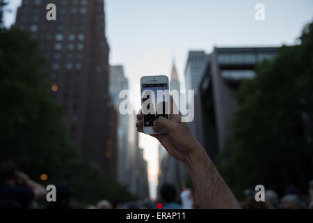 New York, USA. 30 mai, 2015. Un homme attend pour prendre des photos de "anhattanhenge» dans le Manhattan, New York, États-Unis, le 30 mai 2015. Les touristes, les habitants et les banlieusards attendu pour prendre des photos de l'effet "anhattanhenge» mais ont été contrecarrés par les nuages samedi. Le Manhattanhenge renvoie à la deux fois par année au cours de laquelle la circonstance coucher de soleil soit parfaitement aligné avec les rues est-ouest de New York. © Muzi Li/Xinhua/Alamy Live News Banque D'Images