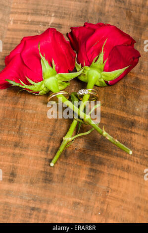 Deux roses rouges avec les anneaux de mariage attaché Banque D'Images