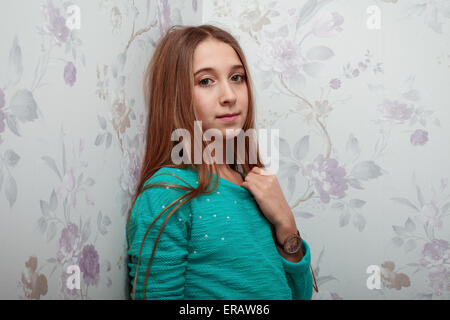 Belle petite fille aux cheveux longs sur un fond floral Banque D'Images