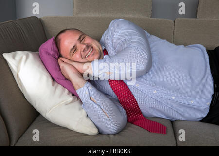 Gros homme en chemise et cravate allongé sur la table et sourit Banque D'Images