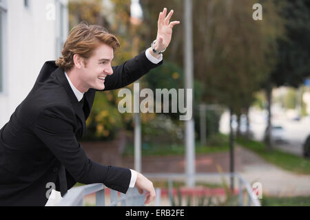 Homme dans un costume noir en agitant à quelqu'un Banque D'Images