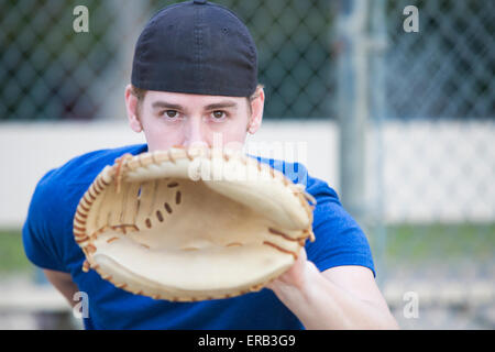 Jeune homme avec un gant de baseball sur un terrain de sport Banque D'Images