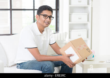 Concept de la livraison de courrier. Guy indiennes a reçu un colis express et cochez la case à la maison. Beau mâle portrait. L'homme asiatique Banque D'Images