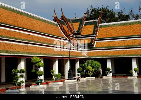 Bangkok, Thaïlande : arbres topiaires, galerie du cloître avec des toits des bâtiments orange, au Wat Suthat Banque D'Images