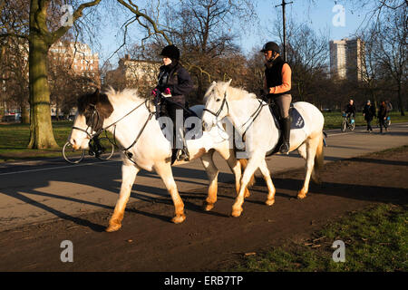 Deux personnes l'équitation dans la région de Hyde Park au centre de Londres, au Royaume-Uni. Suivant le chemin appelé Dorchester Ride, qui est parallèle au Park Banque D'Images