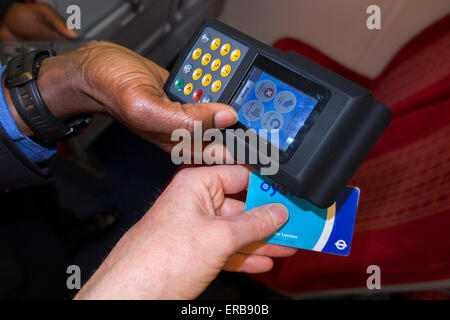 Inspector vérifie / lit carte Oyster ticket avec reader sur SW Trains train aérien également valide LT /bus voyage tube souterrain Banque D'Images