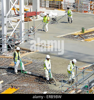 Construction bâtiment industrie lieu de chantier et vibrer le béton pompé dans le renforcement avec les travailleurs de la flotte de puissance finition lisse plancher bande Londres UK Banque D'Images