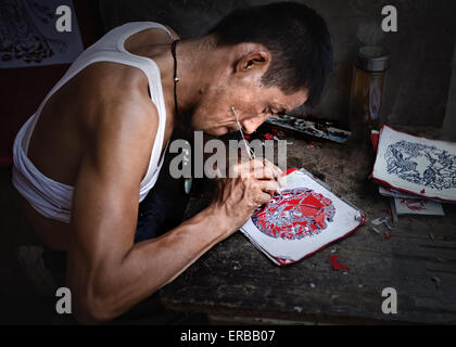 Les hommes faisant un découpage de papier traditionnel de la Chine dans son atelier d'art Banque D'Images