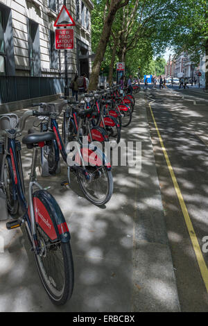 Cycles de Santander la queue à une station d'accueil sur une rue bordée d'arbres dans le centre de Londres Banque D'Images