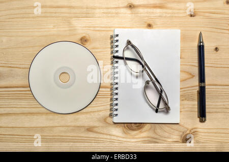 Kit papeterie vierge : lunettes, CD, ordinateur portable, et crayon sur table en bois. Banque D'Images