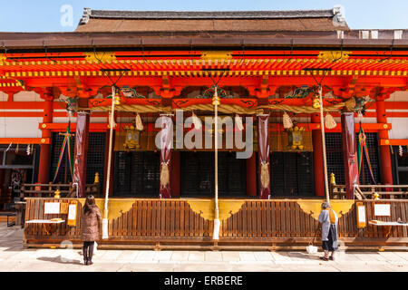 Les gens priaient devant le vermilion Gion-zukuri, le principal hall du célèbre sanctuaire Shinto Yasaka à Kyoto. Printemps, soleil éclatant Banque D'Images