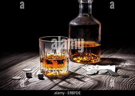 Verre et la bouteille de whisky et de cartes à jouer et de l'argent sur la table en bois Banque D'Images