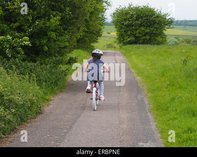 Une jeune fille monte un vélo sur un chemin de campagne Banque D'Images