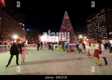 Les familles et les couples profiter de la patinoire au pied de la tour de télévision de Odori Park au cours de l'hiver Snow Festival, Sapporo, Japon. Banque D'Images