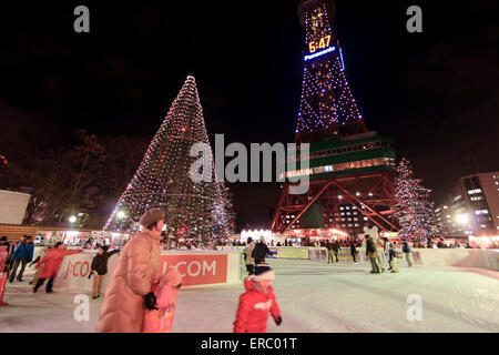 Les familles et les couples profiter de la patinoire au pied de la tour de télévision de Odori Park au cours de l'hiver Snow Festival, Sapporo, Japon. Banque D'Images