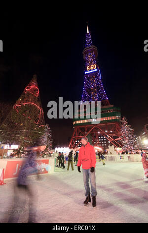 Les familles et les couples profiter de la patinoire au pied de la tour de télévision de Odori Park au cours de l'hiver Snow Festival, Sapporo, Japon. Banque D'Images