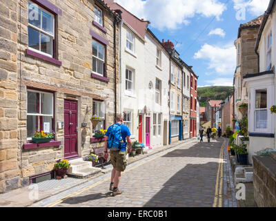 Un homme à Staithes High Street, qui fait partie de la Cleveland Way walking route, sur un après-midi de printemps ensoleillé Banque D'Images