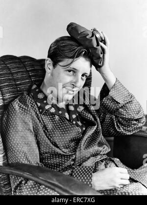 1940 SMILING MAN WITH GUEULE maux de tête à la caméra au sac de glace sur sa tête portant des pyjamas et robe en soie Banque D'Images