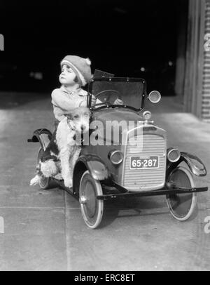 Années 1920 GIRL IN TOY Voiture à pédale AVEC CHIEN ASSIS SUR LE MARCHEPIED EN FILLE À CÔTÉ DE LA TÊTE DE Banque D'Images