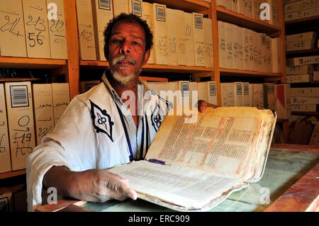 Érudit, vieil homme avec un précieux ouvrage bibliothèque de l'Islam dans le centre historique, Chinguetti, région d'Adrar, Mauritanie Banque D'Images