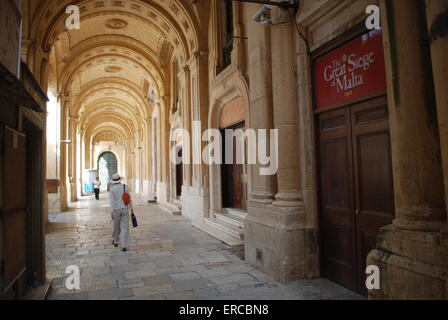Un touriste dans La Valette passe devant une affiche commémorant le 450e anniversaire du Grand Siège de Malte. Pix par : Adam Alexander Banque D'Images