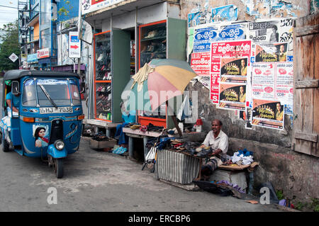 Un rickshaw stationné près d'un réparateur de chaussures au bord du chemin dans la ville de Galle, Sri Lanka Banque D'Images