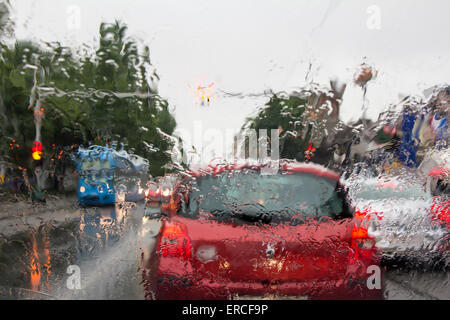 Vu à travers les gouttes d'eau sur le pare-brise de voiture sur des voitures dans la circulation Banque D'Images