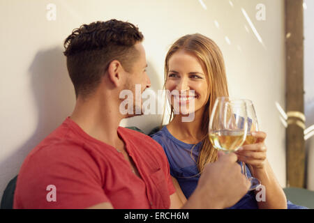 Heureux jeune homme et femme buvant un verre de vin dans leur arrière-cour. Couple toasting with wine and smiling. Banque D'Images