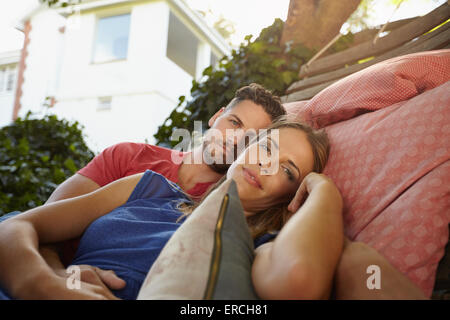 Young caucasian couple romantique de vous détendre sur un hamac ensemble et à la recherche à l'appareil photo. Jeune homme et femme sur la jardin Hamac dans t Banque D'Images