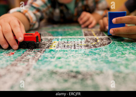 Deux jeunes garçons jouer avec des petites voitures sur une feuille de tableau. Banque D'Images