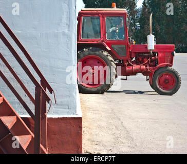 Tracteur rouge se reposant dans un mur blanc Banque D'Images